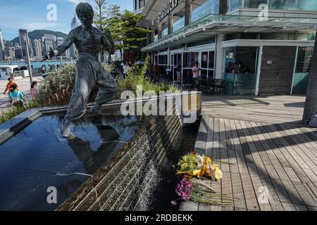 Hongkong, China. 20. Juli 2023 Blumen sind vor der Statue von Bruce Lee in Tsim Sha Tsui zu sehen. Die Regierung Hongkongs feiert den 50. Todestag des Kampfkünstlers Bruce Lee mit einer bedeutenden Ausstellung im Hong Kong Heritage Museum. Die Ausstellung zieht Hunderte von Besuchern an und zollt dem Leben und Vermächtnis des legendären Kampfkünstlers Tribut und fasziniert die Besucher mit Ausstellungen, die seine außergewöhnlichen Leistungen und seinen kulturellen Einfluss zeigen. (Foto: Michael Ho Wai Lee/Alamy Live News Stockfoto