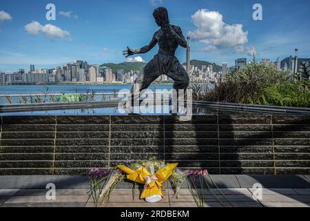 Hongkong, China. 20. Juli 2023 Blumen sind vor der Statue von Bruce Lee in Tsim Sha Tsui zu sehen. Die Regierung Hongkongs feiert den 50. Todestag des Kampfkünstlers Bruce Lee mit einer bedeutenden Ausstellung im Hong Kong Heritage Museum. Die Ausstellung zieht Hunderte von Besuchern an und zollt dem Leben und Vermächtnis des legendären Kampfkünstlers Tribut und fasziniert die Besucher mit Ausstellungen, die seine außergewöhnlichen Leistungen und seinen kulturellen Einfluss zeigen. (Foto: Michael Ho Wai Lee/Alamy Live News Stockfoto