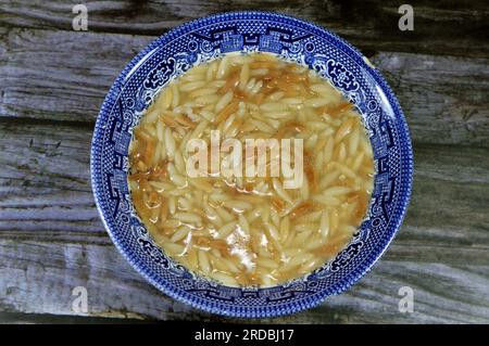 Nahöstliche ägyptische Pasta-Suppe, auch bekannt als Shorbet Lesan El Asfour, traditionelle ägyptische Komfortgerichte aus Orzo Pasta, Butter und Oliven Stockfoto