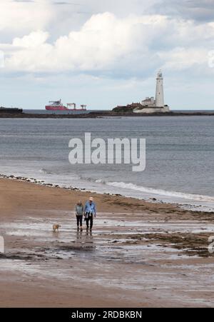 St. Marys Light House Whitley Bay mit ein paar Spazierhunden am Strand Stockfoto