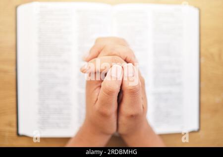 Hände, bibel und Schreibtisch für Gebete, Nahaufnahme und Achtsamkeit für Glauben, Religion oder Lesen in pov. Frau, betet und studiert heiliges Buch für Frieden, geistig Stockfoto