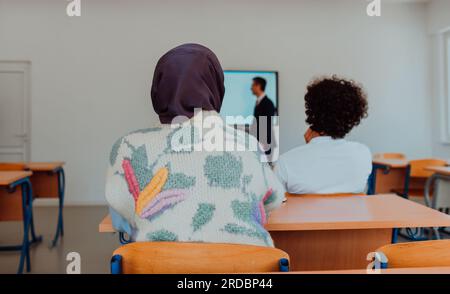 Eine vielfältige Gruppe von Schülern hört aufmerksam zu, nimmt aktiv Teil und begrüßt die moderne Bildung in einem dynamischen Klassenzimmer Stockfoto
