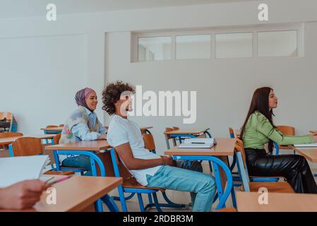 Eine vielfältige Gruppe von Schülern hört aufmerksam zu, nimmt aktiv Teil und begrüßt die moderne Bildung in einem dynamischen Klassenzimmer Stockfoto