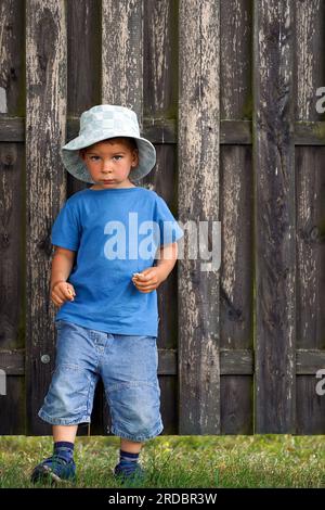 Süßer Junge in Shorts, T-Shirt und panamahut auf dem Land. Stockfoto