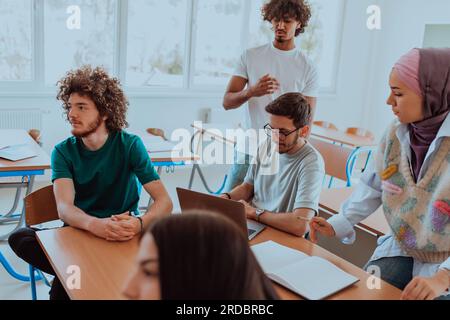 Eine vielfältige Gruppe von Schülern versammelt sich in einem modernen Klassenzimmer und führt leidenschaftlich lebhafte Diskussionen über verschiedene Projekte Stockfoto