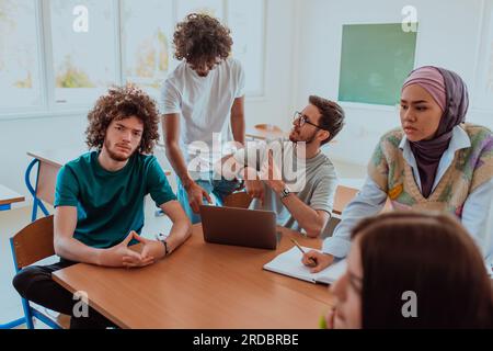 Eine vielfältige Gruppe von Schülern versammelt sich in einem modernen Klassenzimmer und führt leidenschaftlich lebhafte Diskussionen über verschiedene Projekte Stockfoto