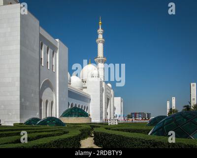 Leuchtend weiße Scheich-Zayid-Moschee mit goldenen Kuppeln am blauen Himmel an einem sonnigen Tag, Abu Dhabi, Vereinigte Arabische Emirate Stockfoto