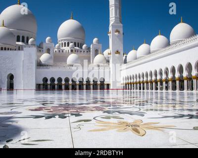 Leuchtend weiße Scheich-Zayid-Moschee mit goldenen Kuppeln am blauen Himmel an einem sonnigen Tag, Abu Dhabi, Vereinigte Arabische Emirate Stockfoto