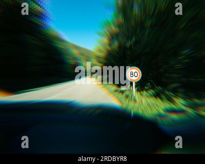 Fokuseffekt auf Geschwindigkeitsbegrenzung über 80kmph km/h auf einer öffentlichen Straße im Wald. Stockfoto