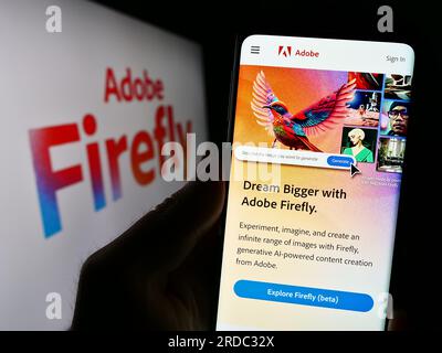 Person, die ein Mobiltelefon mit einer Webseite des generativen KI-Produkts Adobe Firefly auf dem Bildschirm vor dem Logo hält. Konzentrieren Sie sich auf die Mitte des Telefondisplays. Stockfoto