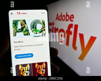 Person, die ein Smartphone mit einer Webseite des generativen KI-Produkts Adobe Firefly auf dem Bildschirm vor dem Logo hält. Konzentrieren Sie sich auf die Mitte des Telefondisplays. Stockfoto