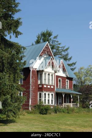 Ein Haus im Lebkuchen-Stil wurde neu gefüttert, um dieses alte Haus zu erhalten. Die rote Farbe blättert von den Seiten ab und spült dieses rote, BL Stockfoto