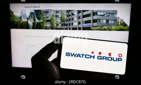 Person, die ein Smartphone mit dem Logo des Schweizer Unternehmens The Swatch Group Ltd. Auf dem Bildschirm vor der Website hält. Konzentrieren Sie sich auf das Display des Telefons. Stockfoto