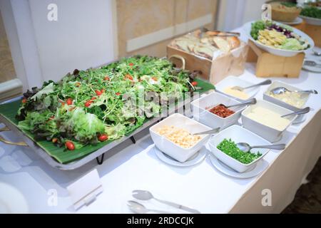 Flacher Schuss verschiedener Gemüsesorten für Salat in der Buffetlinie. Mit einer Schüssel mit anderen Zutaten wie knusprigem Speck, knusprigem Brot, Käse, Salat Stockfoto