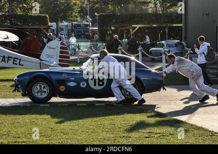 Mechaniker schieben einen klassischen AC Cobra 289 Rennwagen früh am Morgen zum Goodwood Revival 2013. Ereignis wird vorbereitet Stockfoto