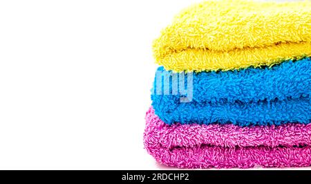 Nahaufnahme von drei Badehandtüchern in verschiedenen Farben, gestapelt auf weißem Hintergrund. Stockfoto