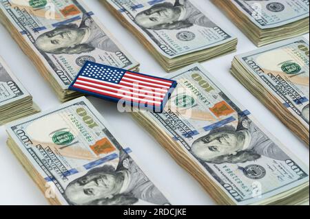 Die amerikanische Flagge auf 100-Dollar-Stapeln lag auf weißem Studiohintergrund Stockfoto