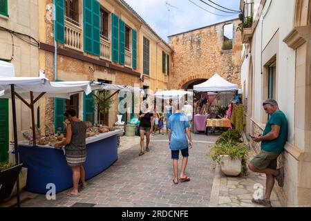 Die Menschen schlendern durch eine gemütliche, enge Straße mit Verkaufsständen in der malerischen Stadt Santanyí auf der Mittelmeerinsel Mallorca in Sp Stockfoto