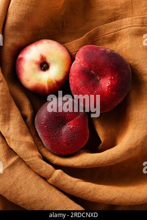 Reife und frische flache Pfirsiche auf einem Leinentuch. Ernte. Obstladen Stockfoto