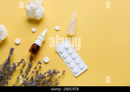 Flaschen mit Tropfen mit Pillen, Blumen und Taschentüchern auf gelbem Hintergrund. Saisonales Allergiekonzept Stockfoto