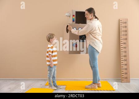 Kindermädchen mit Roboterkostüm aus Pappe und kleiner Junge zu Hause Stockfoto