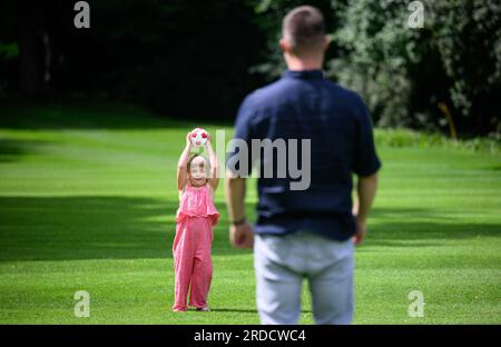 Berlin, Deutschland. 20. Juli 2023. Annabel Rogotzki und Fabian Dancker spielen mit einem Ball im Park des Bellevue Palastes. Annabel, eine transplantierte Blutkrebspatientin, traf ihren Lebensretter Fabian Dancker zum ersten Mal zusammen mit ihren Eltern im Bellevue Palace. Das Mädchen, das jetzt vier Jahre alt ist, litt an Leukämie und brauchte eine Stammzellenspende. Kredit: Bernd von Jutrczenka/dpa - ACHTUNG: Nur zur redaktionellen Verwendung im Zusammenhang mit der aktuellen Berichterstattung und nur mit vollständiger Erwähnung der oben genannten Credits/dpa/Alamy Live News Stockfoto