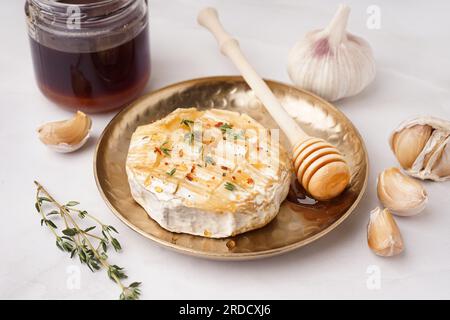 Teller mit leckerem gebackenem Camembert-Käse auf grauem Hintergrund Stockfoto