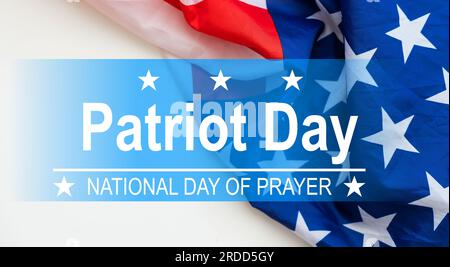 Die Worte Patriot Day 09.11.01 wurden mit silbernen Metallbuchstaben auf Holzbrettfläche mit zerknitterter us-Flagge unten mit Nahaufnahme diagonaler Perspektive gelegt Stockfoto