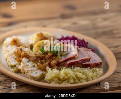 Geräuchertes Fleisch, serviert mit Rot- und Weißkohl und zwei Sorten Knödel Stockfoto