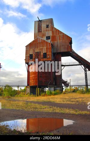 Verlassenes Osceola Copper Mine Gesteinshaus steht rostend und unbenutzt. Schlammpfütze reflektiert Gebäude. Stockfoto