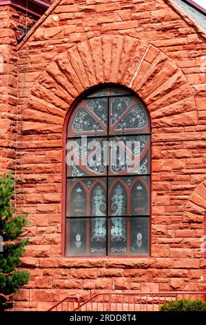 Das Buntglasfenster in der Grace United Methodist Church in Houghton, Michigan, wird von Jacobsville Sandstein eingerahmt. Stockfoto