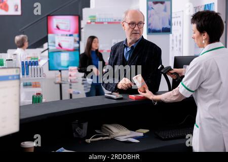 Älterer Mann gibt Apothekenkasse medizinisches Produkt zum Scannen an der Kasse und diskutiert Sonnencreme mit pharmazeutischem Arbeiter. Kunde besucht Drogerie, um Sonnenschutzlotion und Vitamin zu kaufen Stockfoto