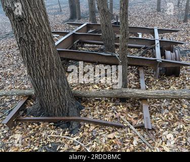Bäume in einem Wald übernahmen den letzten Parkplatz für diesen lange verlassenen, verrosteten, verrotteten Wohnwagen. Stockfoto