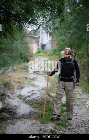 Ein einsamer Mann verlässt El Acebo de San Miguel auf einem felsigen Pfad entlang des Camino nach Santiago de Compostela, Spanien Stockfoto