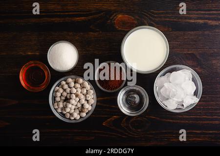 Eisgekühlter Dalgona-Kaffee mit Boba-Zutaten auf Holzhintergrund: Instantkaffee, Zucker, Mil und andere Kaffeezutaten mit Schlagseite Stockfoto