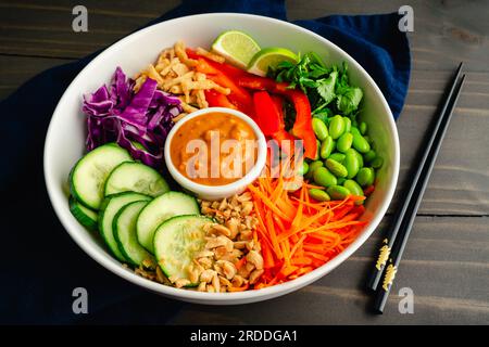 Reis-Nudelsalat mit würziger Erdnusssoße mit Essstäbchen: Veganer Salat mit Reisnudeln garniert mit Edamam, Karotten und anderem frischen Gemüse Stockfoto