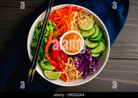Reis-Nudelsalat mit würziger Erdnusssoße mit Essstäbchen: Veganer Salat mit Reisnudeln garniert mit Edamam, Karotten und anderem frischen Gemüse Stockfoto