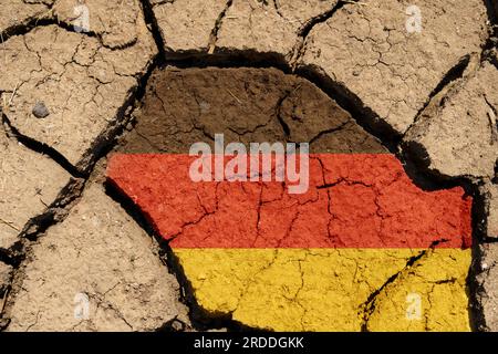 Ökologisches Konzept. Dürre. Auf trockenem, gerissenem Boden das Bild der deutschen Flagge. Stockfoto