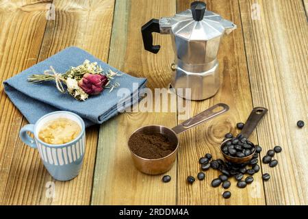 Ein Stillleben mit geröstetem Kaffee, gemahlenem Kaffee in einem Kupfertopf, einem Espresso in einer blauen Tasse und einer kleinen Kaffeekanne Stockfoto