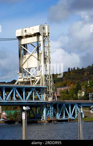 Portage Lake wird von der Portage Lake Lift Bridge bedient, die Hancock und Houghton, Michigan, verbindet. Quincy Hill im Hintergrund ist im Herbst bedeckt Stockfoto