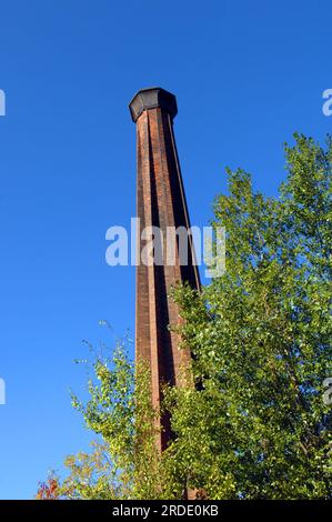 Ein hoher, vom blauen Himmel umrahmter Rauchschornstein repräsentiert die Industrie der vergangenen Tage. Smokestack ist Teil der Calumet und Hecla County Copper Mine in Cal Stockfoto