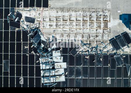 Draufsicht der durch den Hurrikan Ian zerstörten Photovoltaik-Solarpaneele, die auf dem Dach des Industriebaues zur Erzeugung von ökologischem Strom montiert sind Stockfoto