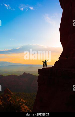 Silhouette von Vater und Tochter auf dem Weg am Cathedral Rock bei Sonnenuntergang in Sedona. Der farbenfrohe Sonnenuntergang über Sedonas Cathedral Rock Wahrzeichen. Stockfoto