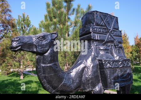 Nahaufnahme, Detailansicht eines typischen Kamels mit Gütern, Fracht, Kisten bei der Caravan Silk Road Skulpturenprozession. Im Ethno Historic Complex Park Stockfoto