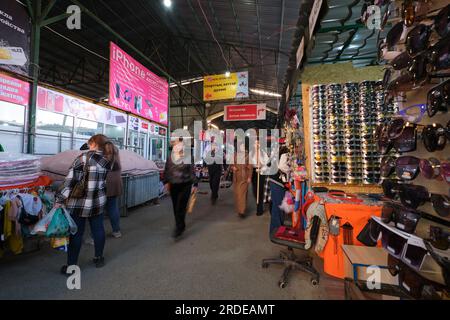 Käufer, die an einem typischen, billigen Sonnenbrillen-Laden vorbeikommen. Im großen Qyrgy-Basar in Shymkent, Kasachstan. Stockfoto