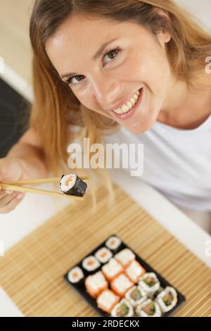 Bild einer Frau, die Sushi mit Essstäbchen isst Stockfoto
