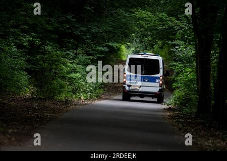 Berlin, Deutschland. 21. Juli 2023. Ein Polizeiwagen fährt durch den Wald in Berlin-Zehlendorf, nahe der Südgrenze Berlins. Ein gefährliches wildes Tier soll am Donnerstagabend in Brandenburg entkommen sein, was eine große Suchaktion ausgelöst hat. Kredit: Fabian Sommer/dpa/Alamy Live News Stockfoto