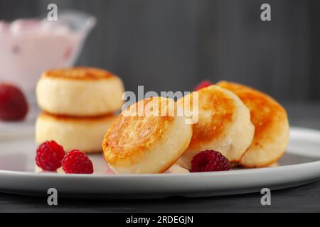 Hüttenkäse-Pommes oder Syrniki mit Joghurt und Himbeeren, Seitenblick. Stockfoto