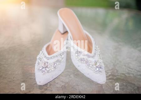 Hochzeitsschuhe mit spitzen Zehen. Schuhe mit hohen Absätzen. Frauenfüße in luxuriösen Sommerschuhen für Damen. Elegante Hausschuhe für Damen auf dem Boden. Fash Stockfoto