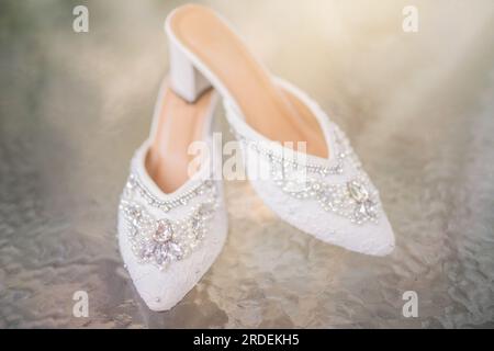 Hochzeitsschuhe mit spitzen Zehen. Schuhe mit hohen Absätzen. Frauenfüße in luxuriösen Sommerschuhen für Damen. Elegante Hausschuhe für Damen auf dem Boden. Fash Stockfoto